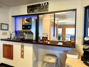 A coffee bar with a coffee machine, a mirror, and a view of the outside.