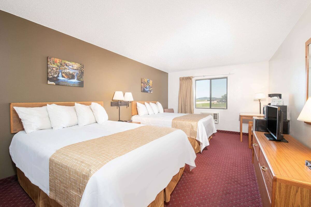 Une chambre d’hôtel avec deux lits, un bureau avec une télévision et une fenêtre donnant sur un paysage agréable.
