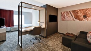 Een hotelkamer met een bed, bureau, stoel, televisie en een groot raam.