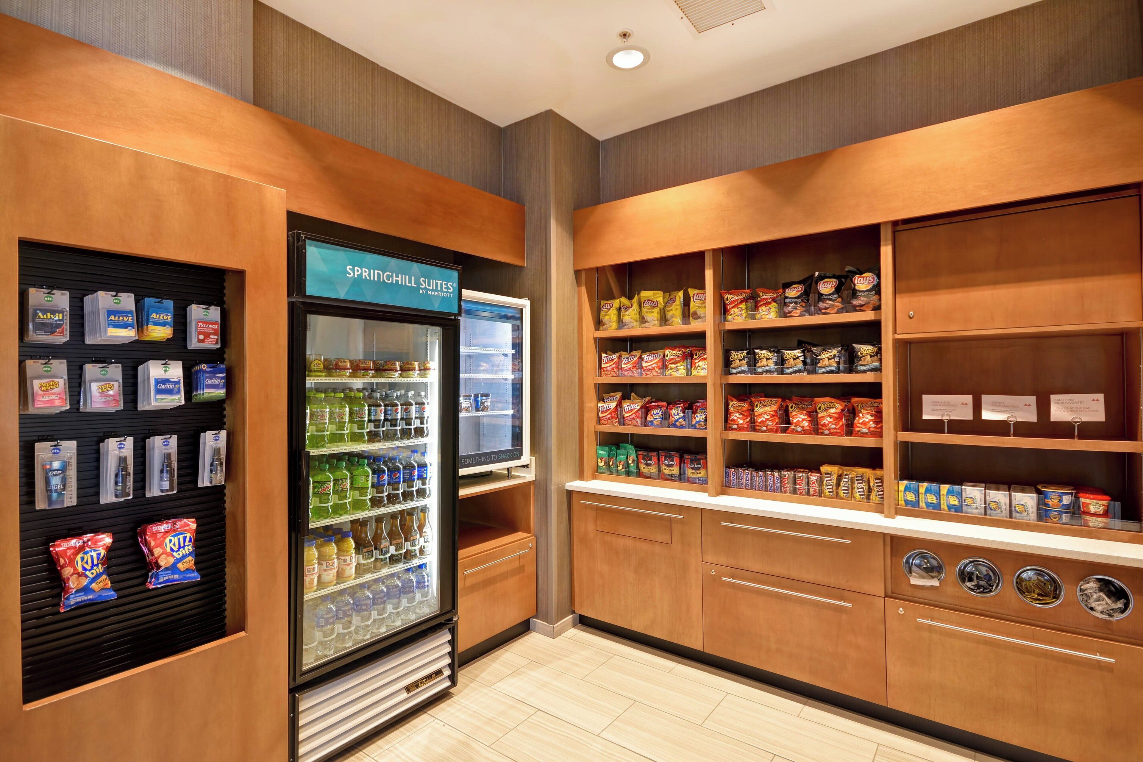 A kitchenette with a refrigerator, shelves stocked with snacks, and a coffee machine.