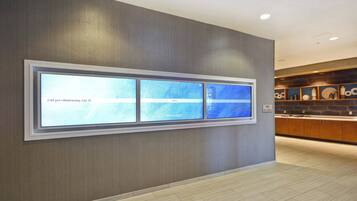 A modern hotel corridor with a digital display wall and a well-lit kitchen area.