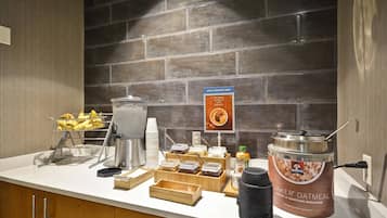 A breakfast buffet setup with various food items and a Quaker Oatmeal container.
