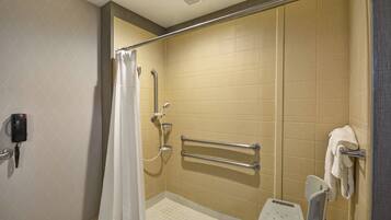 A handicap-accessible shower with grab bars, a shower chair, and a towel rack.