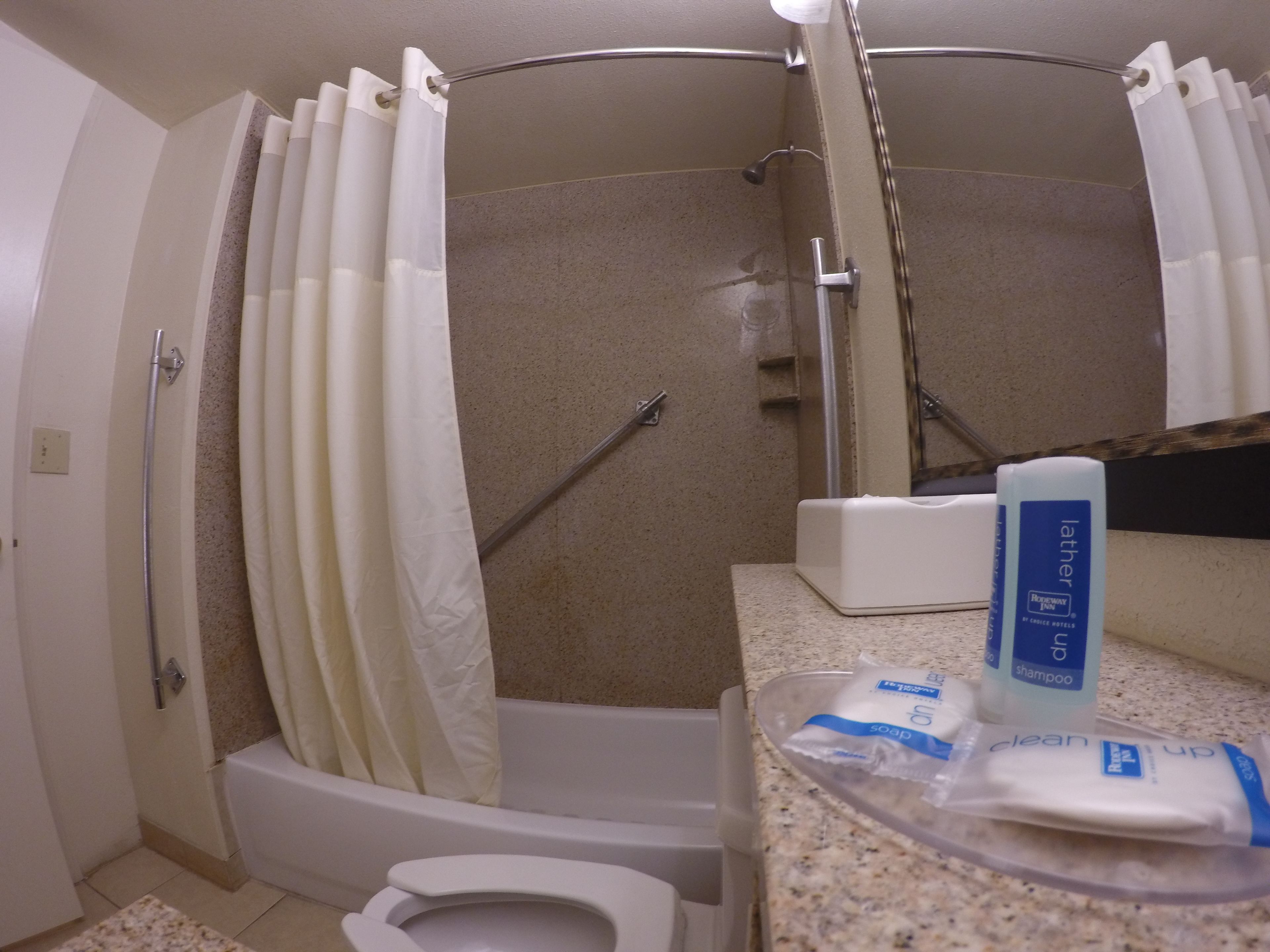 A bathroom with a shower, toilet, and a sink with toiletries.