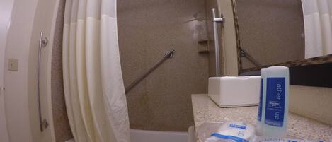 A bathroom with a shower, toilet, and a sink with toiletries.