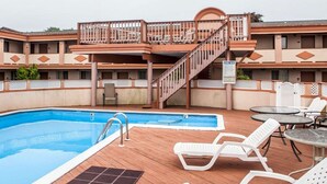 A hotel with a swimming pool, lounge chairs, and a covered deck area. - Rodeway Inn Point Pleasant Beach (Point Pleasant Beach)