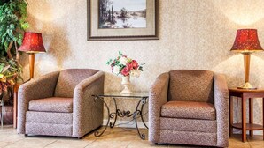 A room with two armchairs, a glass table with a vase of flowers, and two lamps. - Rodeway Inn Point Pleasant Beach (Point Pleasant Beach)