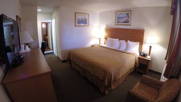A hotel room with a bed, a desk with a telephone, a chair, and two wall-mounted lamps.