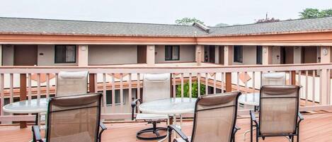 A deck with outdoor seating and a view of a building with multiple balconies.