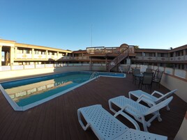Una piscina al aire libre de temporada, sillones reclinables de piscina