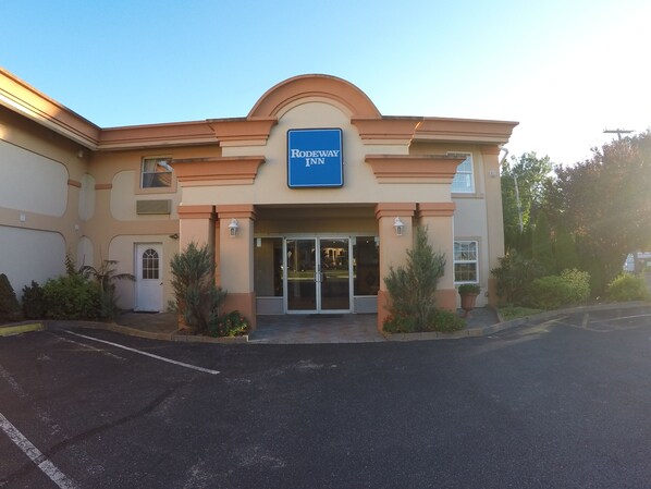 A Rodeway Inn building with a large entrance, a parking lot, and landscaping. - Rodeway Inn Point Pleasant Beach (Point Pleasant Beach)