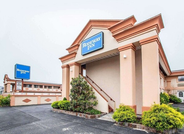 A Rodeway Inn entrance with a sign, a staircase, and a parking lot.