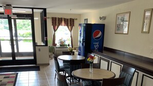 A hotel lobby with a reception desk, seating area, and a Pepsi vending machine. - Amelia Inn & Suites (Amelia Court House)