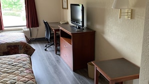 A hotel room with a bed, a desk with a computer, a chair, a TV, and a lamp. - Amelia Inn & Suites (Amelia Court House)