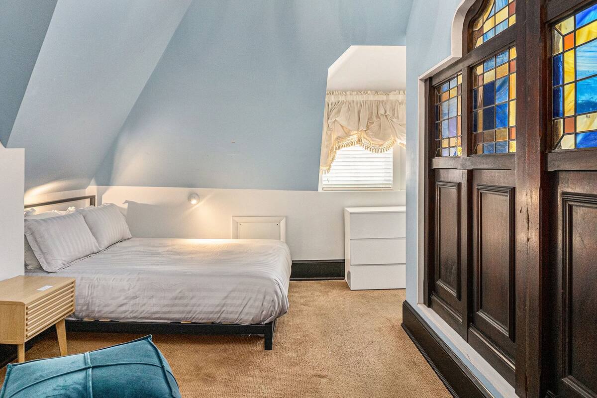 Une chambre à coucher avec un lit, une table de chevet et une fenêtre avec un rideau.