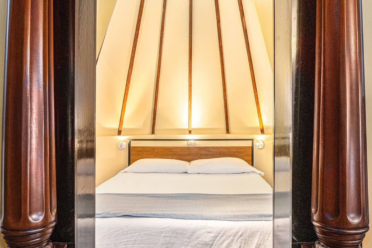 Un lit bien fait, avec une tête de lit en bois et un baldaquin au-dessus.