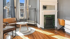 A modern living room with a fireplace, a sofa, a coffee table, and a view of the city through large windows.