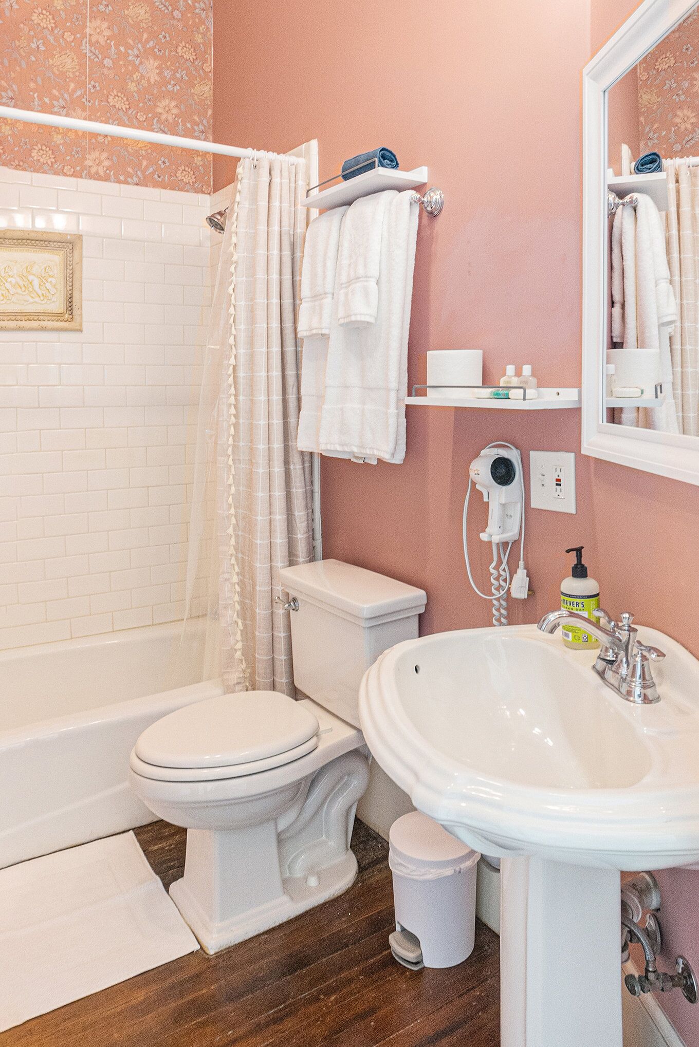 A bathroom with a white toilet, a white sink, a shower with a beige curtain, and a mirror above the sink.
