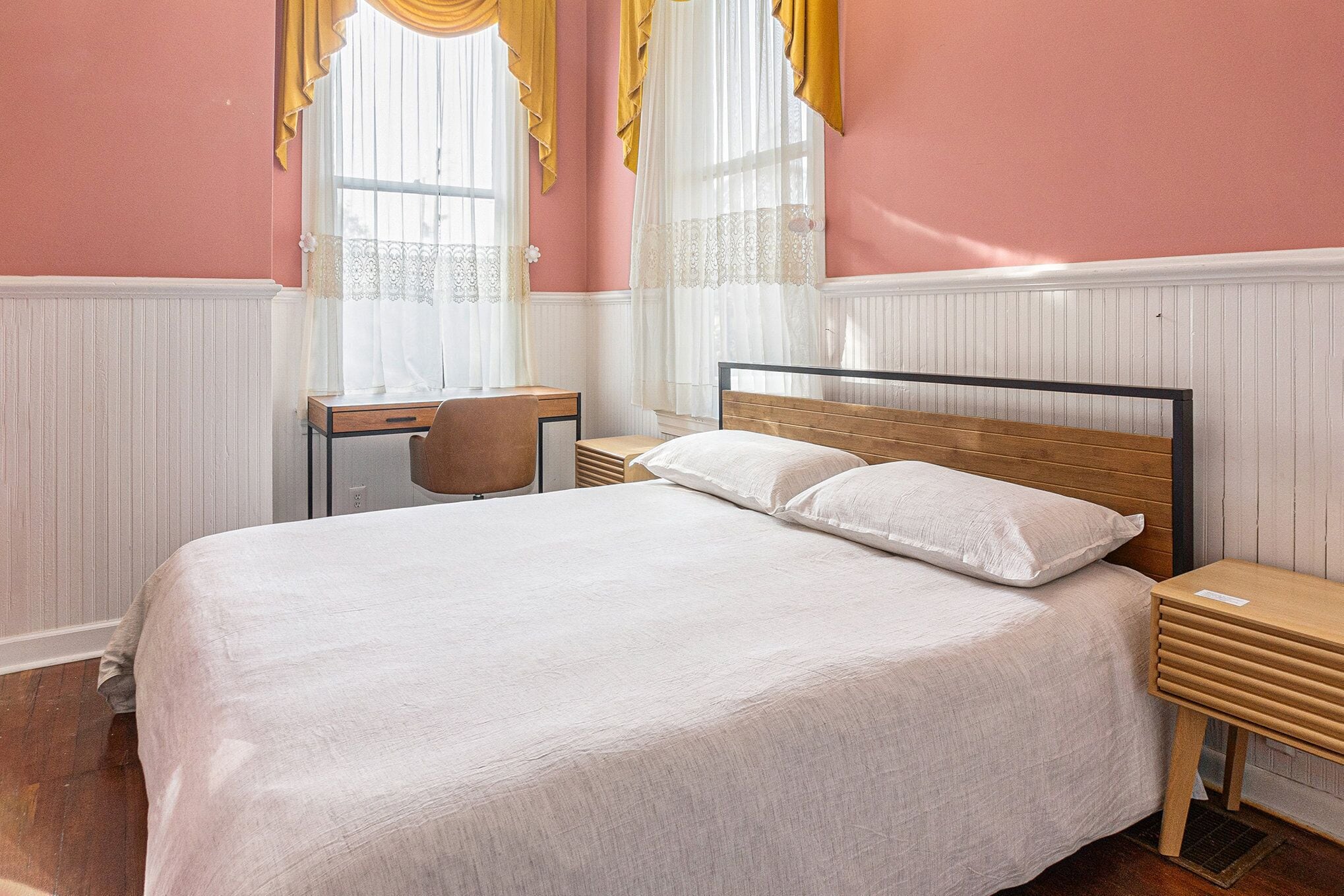 A bedroom with a bed, bedside tables, a desk, and a chair.