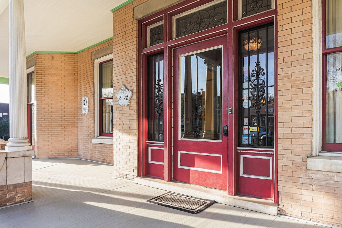 A building with a red door, a mailbox, and a number sign.