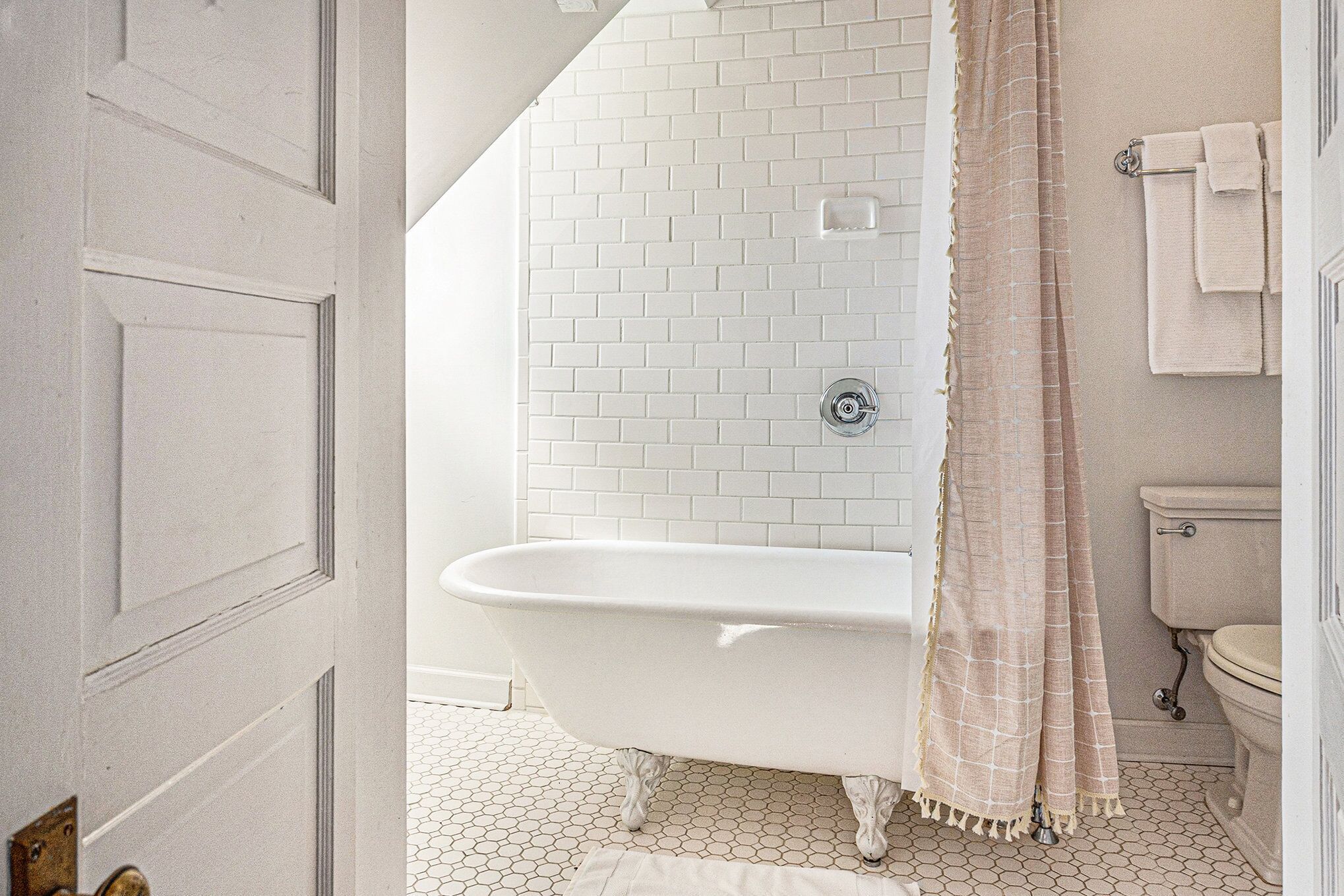 A bathroom with a white bathtub, a toilet, and a shower curtain.