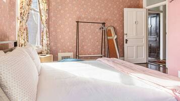 Une chambre à coucher comprenant un lit, une table de chevet, un miroir et une porte donnant sur une autre pièce.