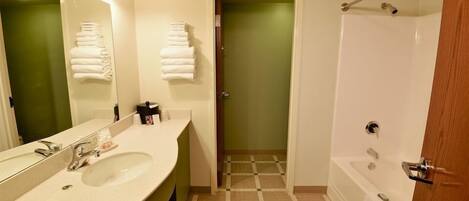 A bathroom with a sink, mirror, towel rack, and a shower area.