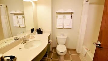 Une salle de bain équipée d’un lavabo, d’un miroir, de toilettes et d’un espace douche.