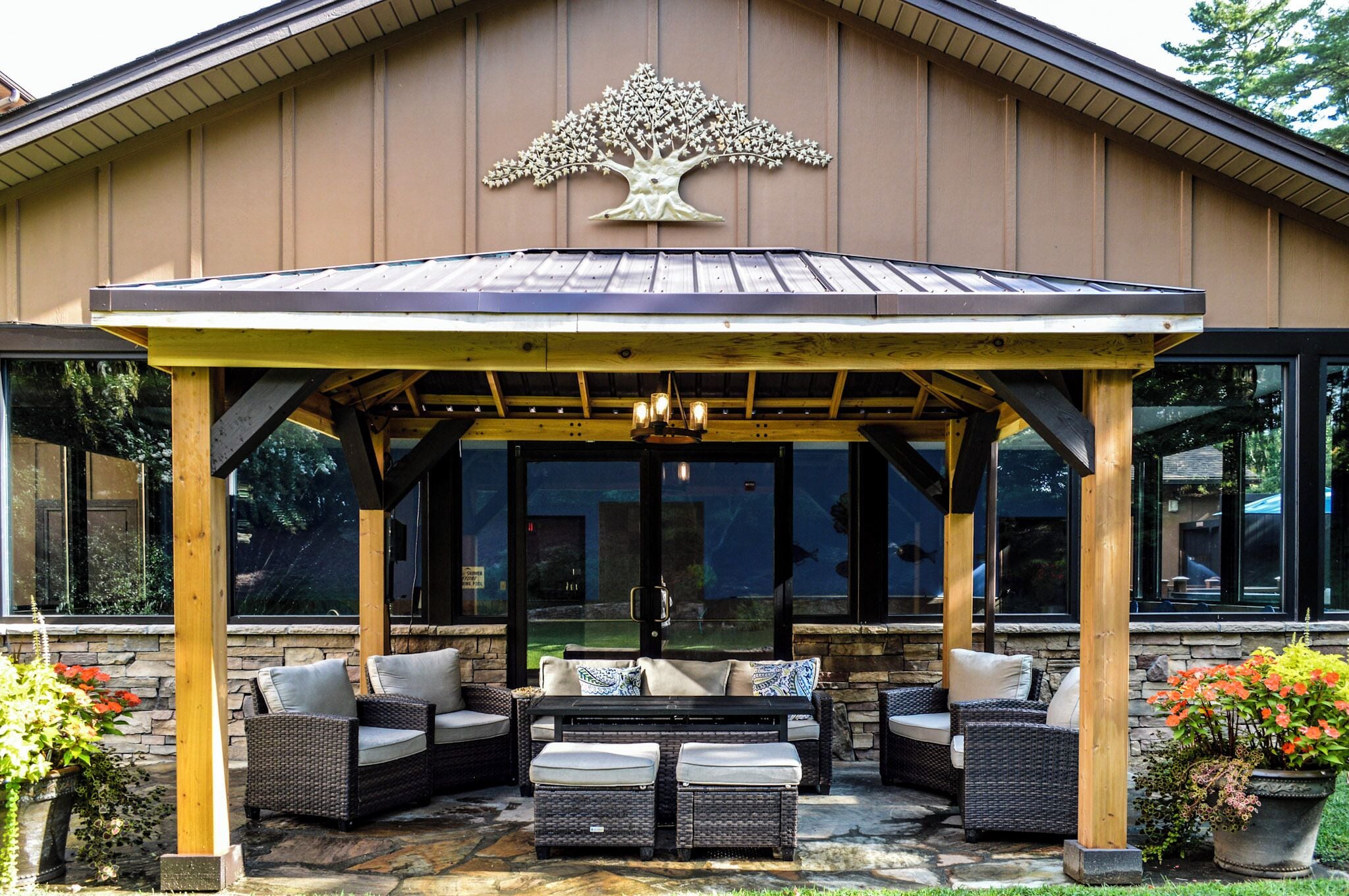 A covered patio area with outdoor furniture, a pergola, and a decorative tree sculpture.