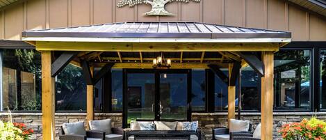 A covered patio area with outdoor furniture, a pergola, and a decorative tree sculpture.