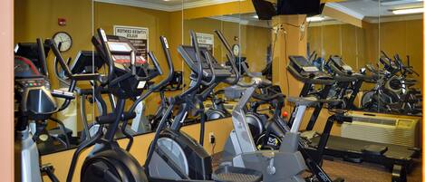 Un gimnasio con varias bicicletas estáticas y cintas de correr.