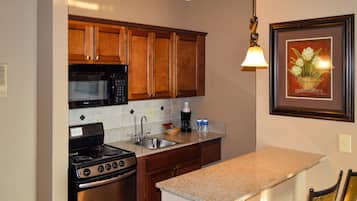Una cocina con armarios de madera, un lavamanos de acero inoxidable, un microondas y una estufa.