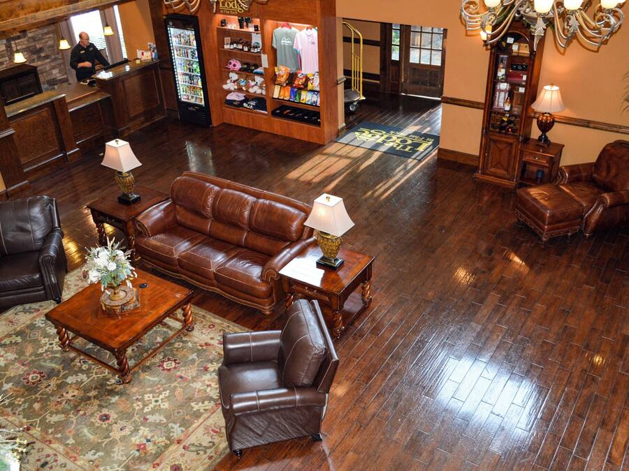 Un hall con un sofá de cuero marrón, dos sillones, una mesa de centro de madera y un mostrador de recepción.