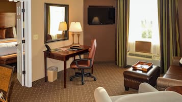 A hotel room with a bed, desk, chair, TV, and a window with curtains.