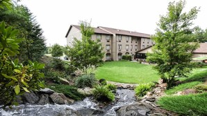 A hotel with a courtyard, a small stream, and surrounding greenery. - The Lodge at Flat Rock (Flat Rock)