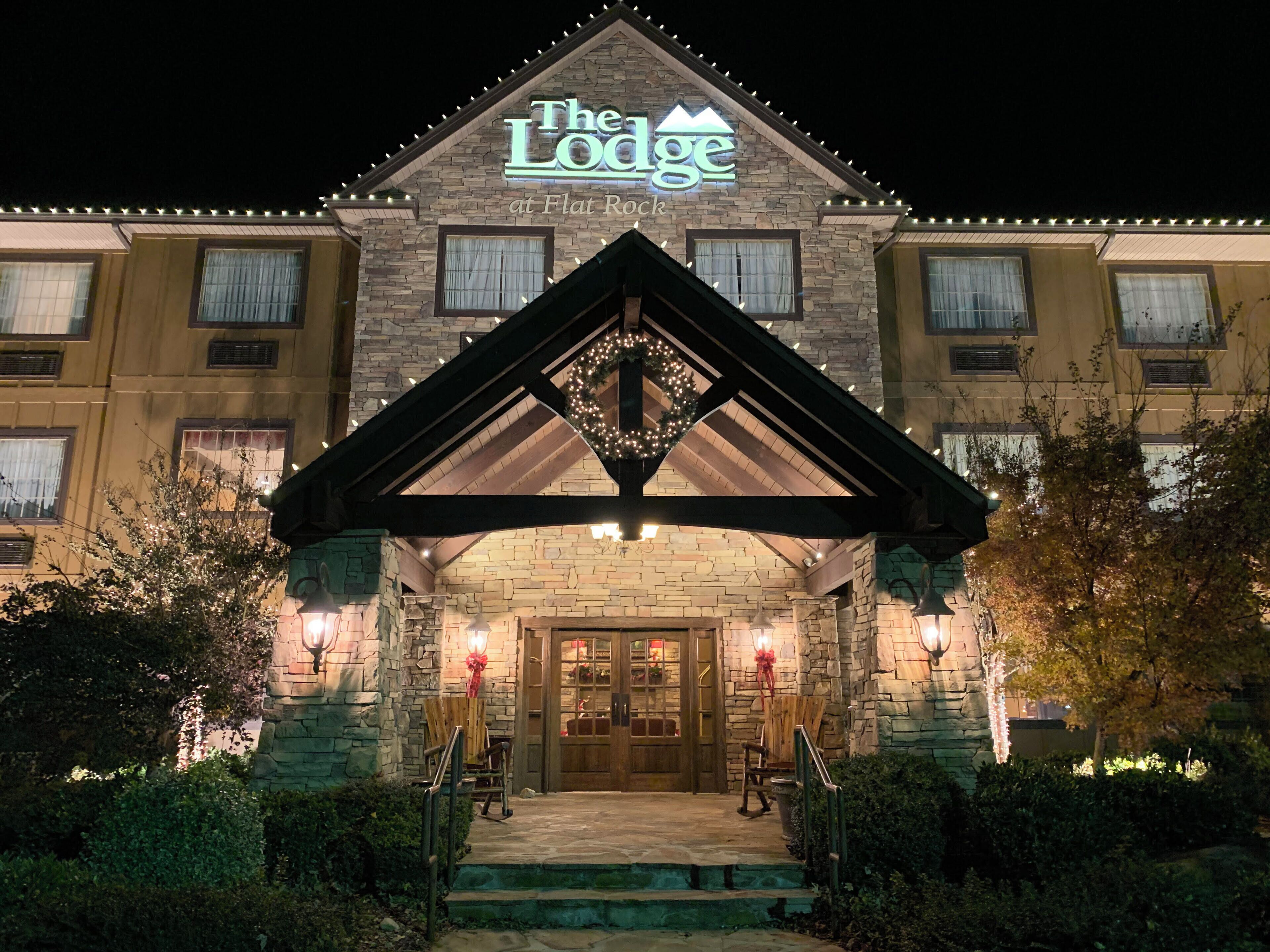 The Lodge at Flat Rock with a stone facade, a wooden entrance, and a sign above the door.