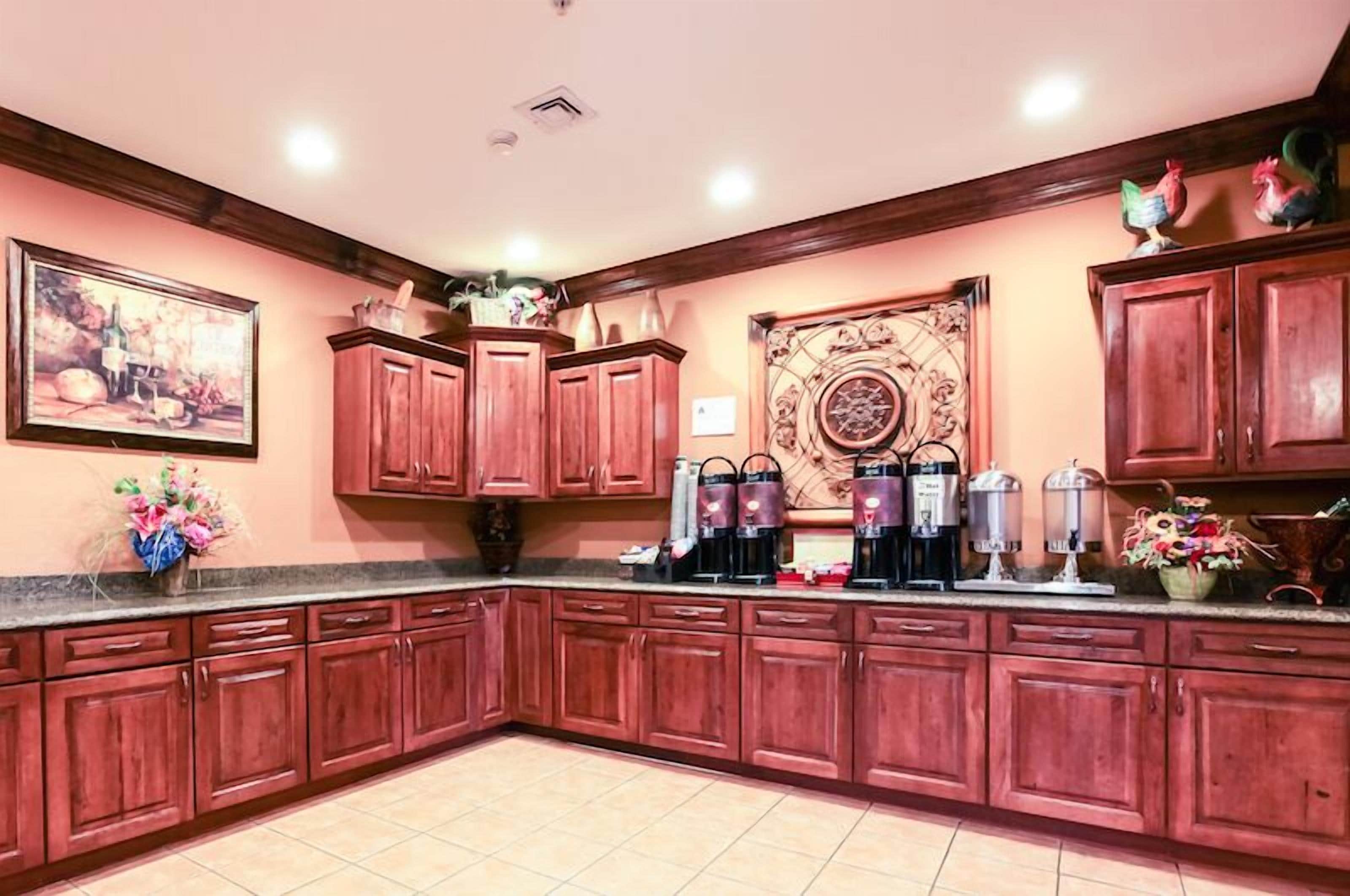 Una cocina con armarios de madera, una estación de café y un elemento decorativo en la pared.