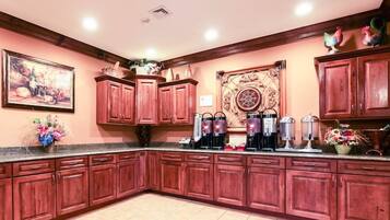 Una cocina con armarios de madera, una estación de café y un elemento decorativo en la pared.