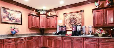 A kitchen with wooden cabinets, a coffee station, and a decorative wall piece.