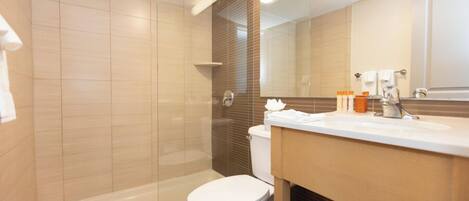 A modern bathroom with a glass shower enclosure, a white toilet, and a vanity with a mirror.