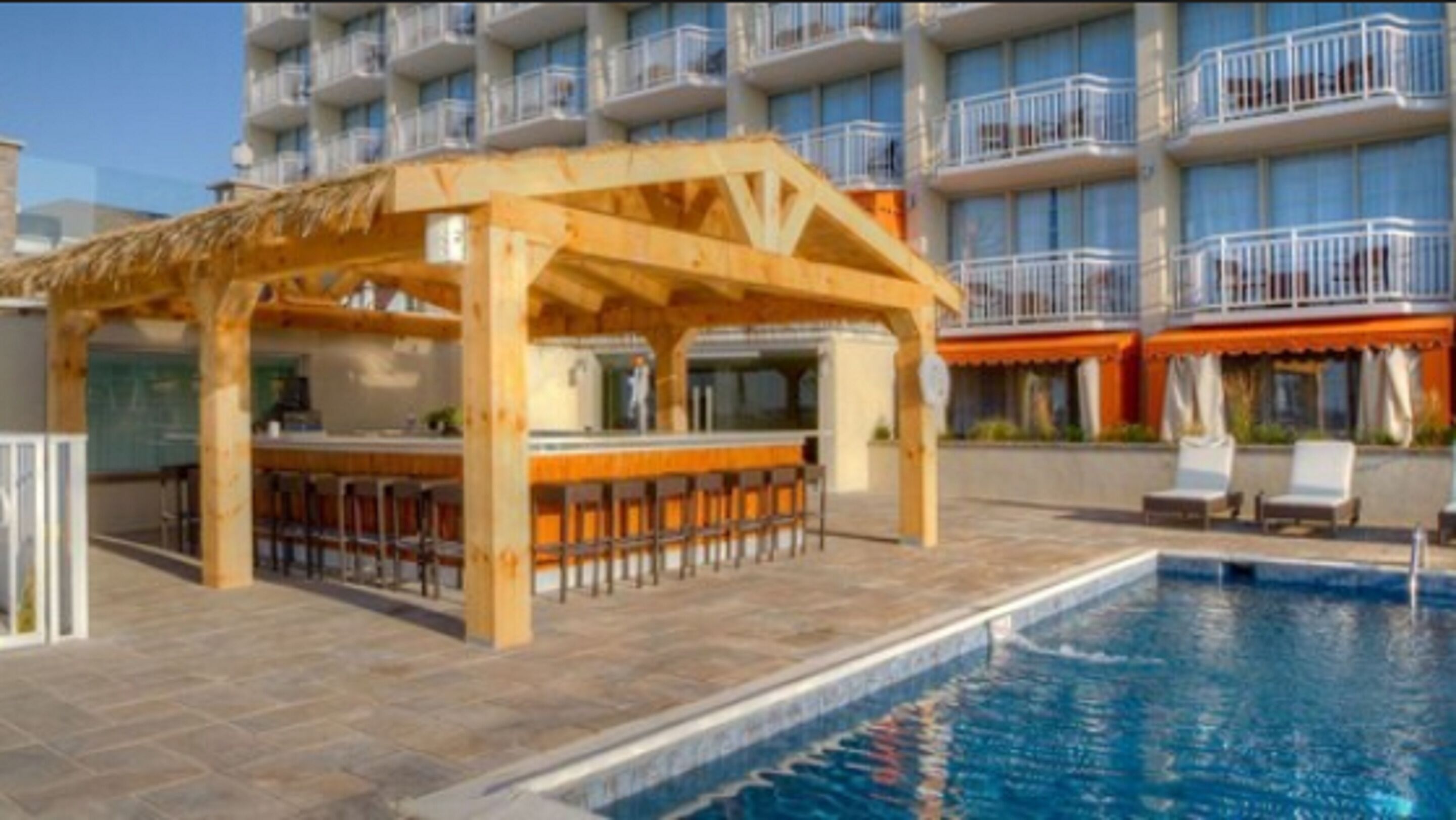 Ein Poolbereich mit einer Holzbar und Liegestühlen.