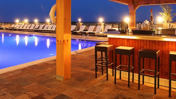 An outdoor pool area with lounge chairs and a bar. - Ocean Club Hotel (Cape May)