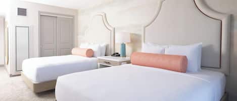 Une chambre d’hôtel avec deux lits, une table de chevet, une lampe et une porte.