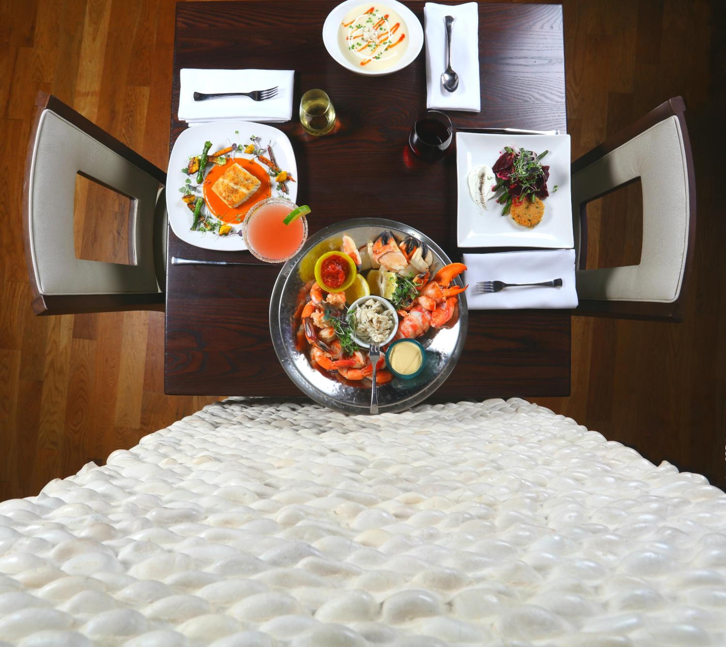 A dining table with seafood, a salad, and a soup dish.