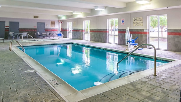 Una piscina interna con acqua cristallina, una postazione per bagnini e un cartello che vieta i tuffi sulla parete.