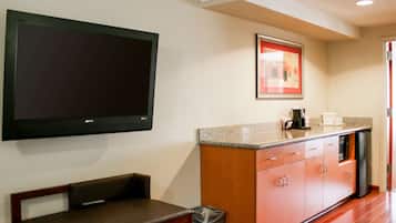 A modern kitchen with a flat-screen TV, a framed picture, a sink, and a bench.
