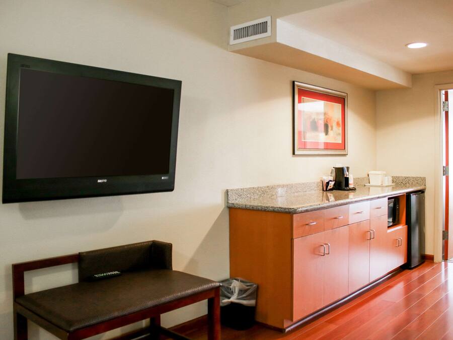 A modern kitchen with a flat-screen TV, a framed picture, a sink, and a bench.