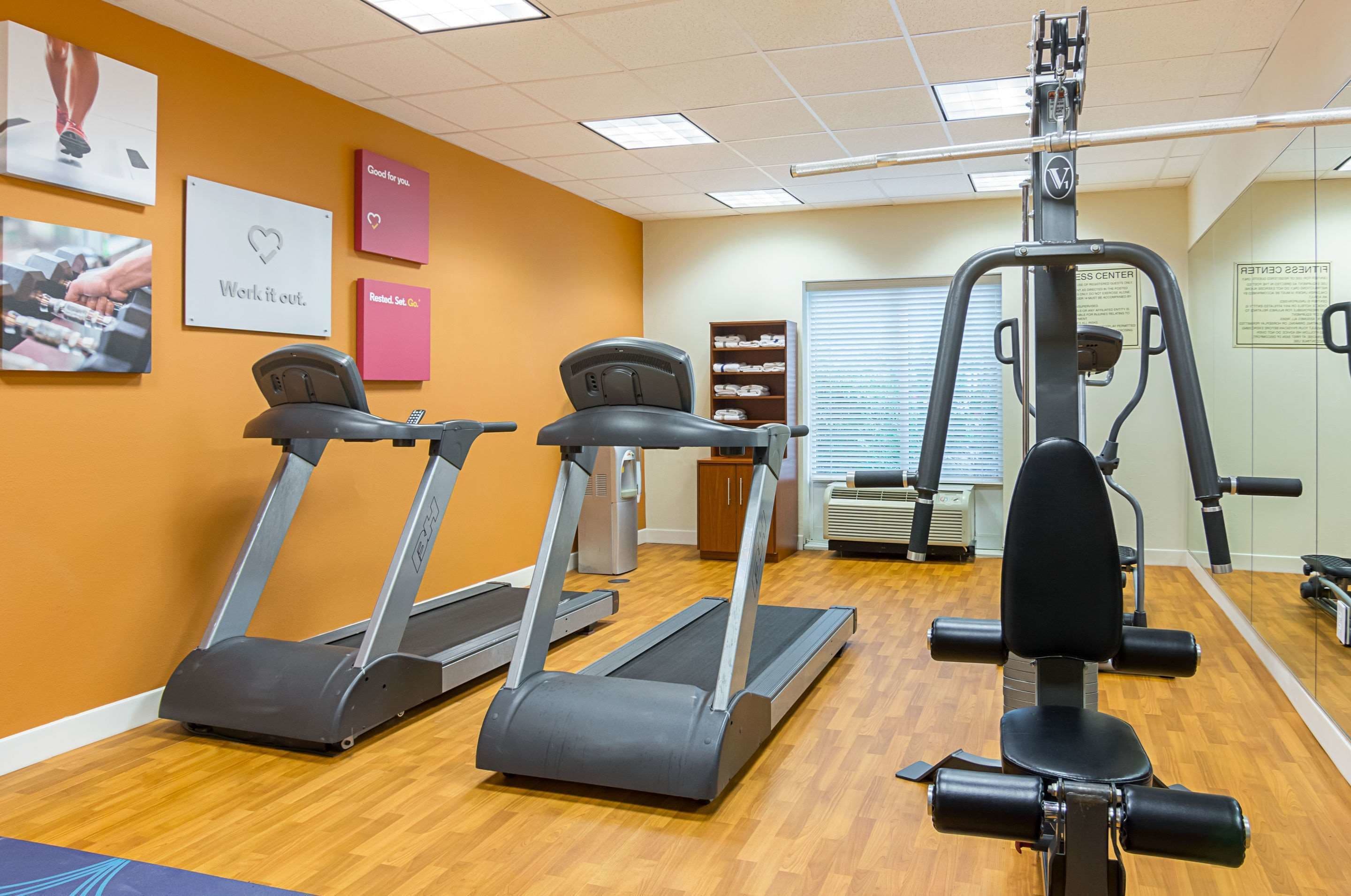 A gym with treadmills, a weight machine, and motivational posters on the wall.