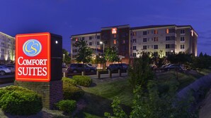 Un hotel Comfort Suites con un cartello ben visibile, diversi piani e un'area di parcheggio.