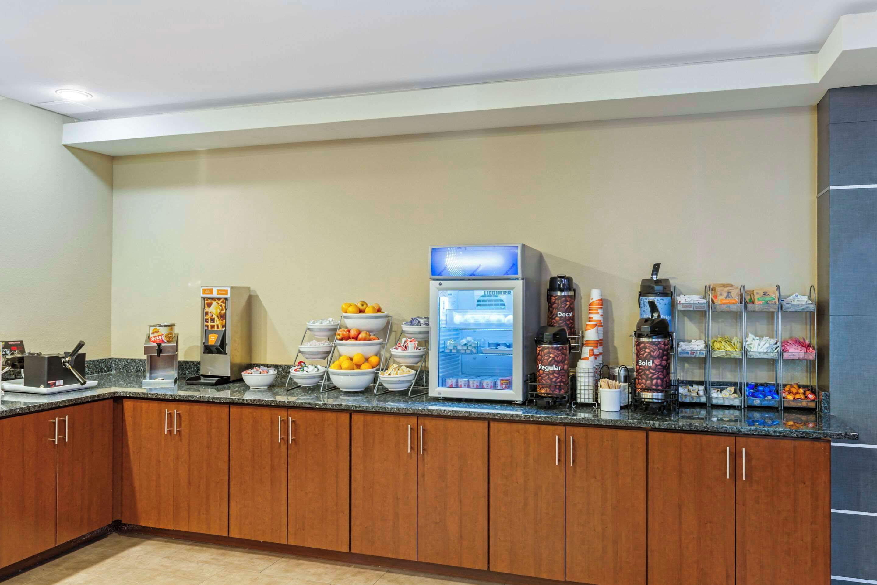 A buffet setup with various food items, a beverage dispenser, and a coffee machine.
